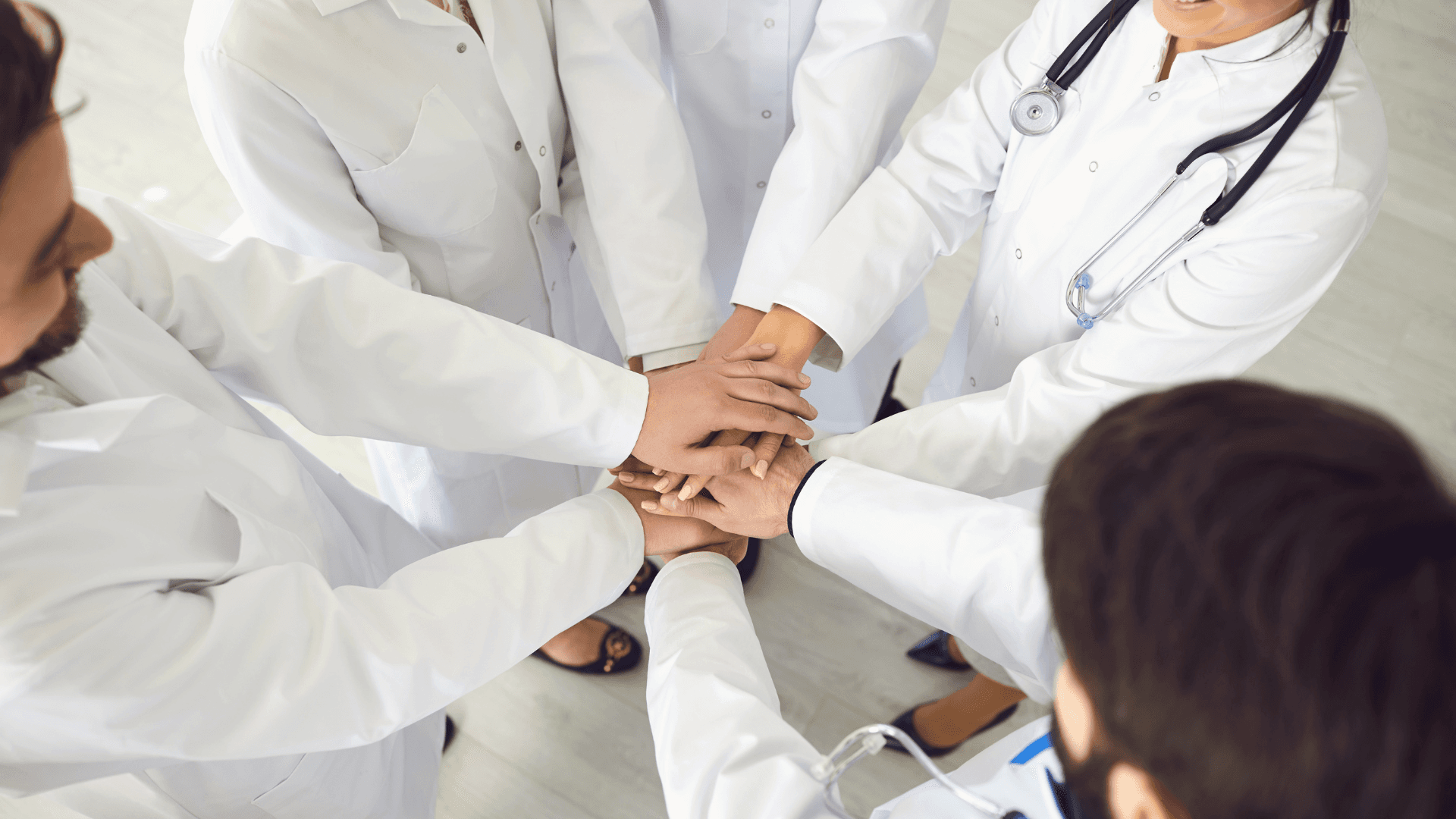 Eine Gruppe von Ärzten reicht sich die Hände.